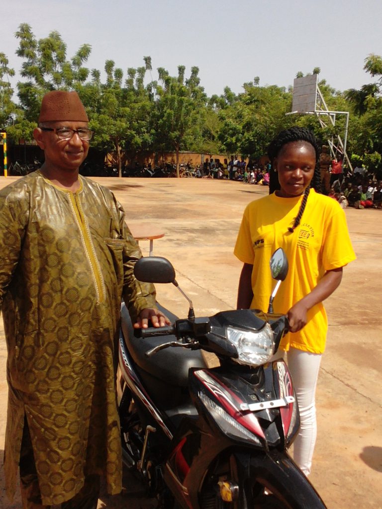 Le président de la cérémonie, Abdoul Salam Boly remettant à une lauréate une moto.